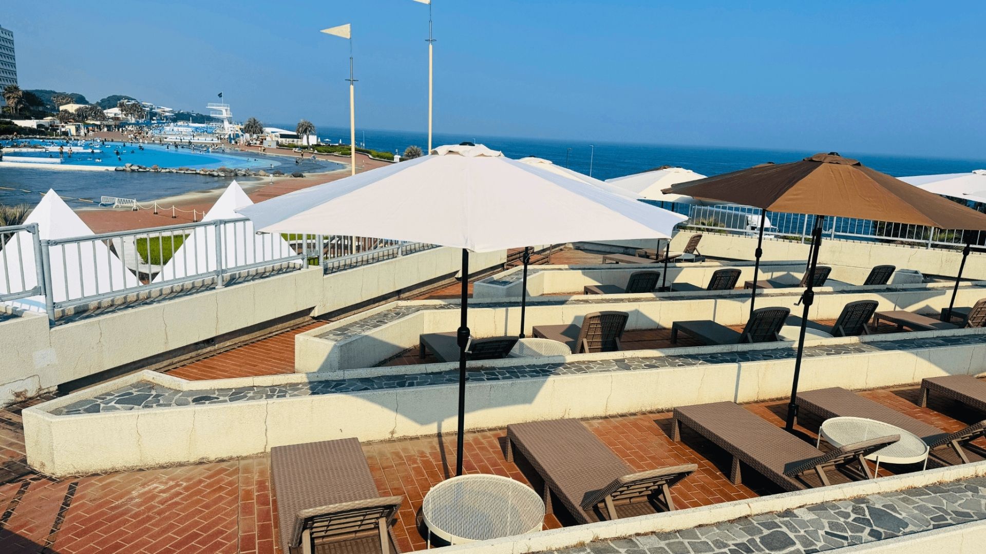 OISO BEACH SIDE BBQのパラソルエリア。パラソルとデッキチェアが並ぶ休憩スペース